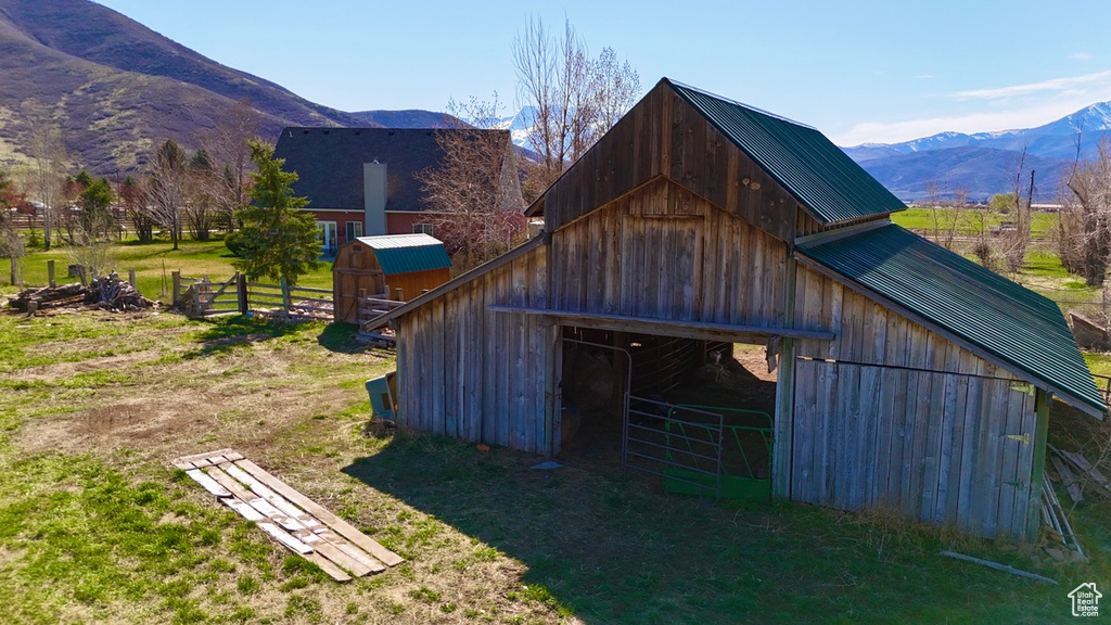 View of barn with a mountain view and fence