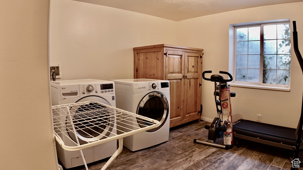 Washroom with cabinet space, washing machine and clothes dryer, wood finished floors, and baseboards