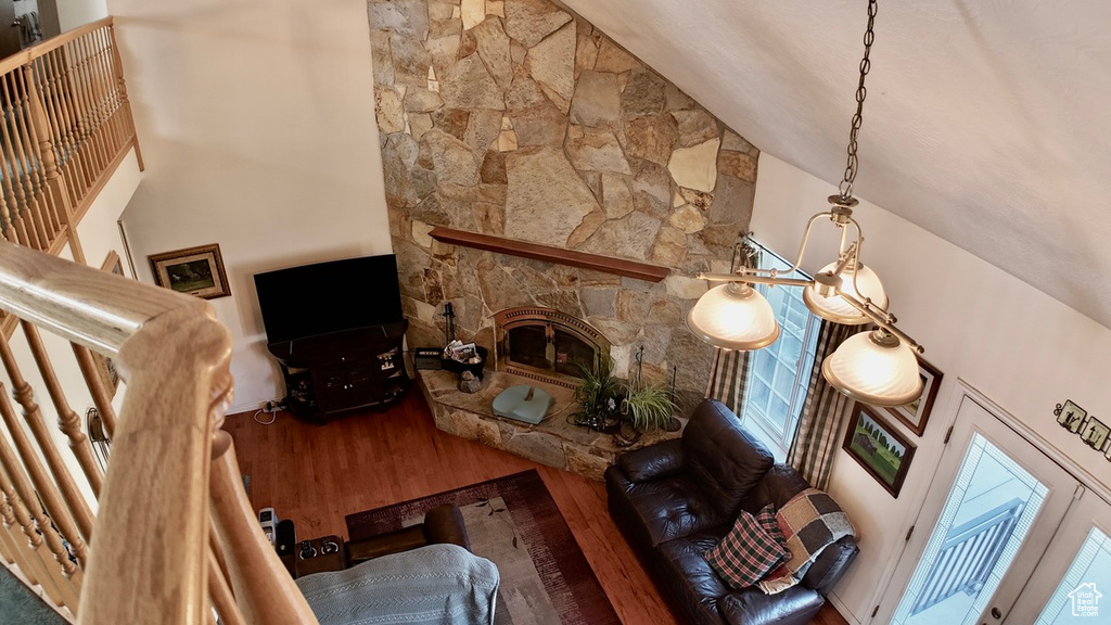 Living room with high vaulted ceiling, a fireplace, and wood finished floors
