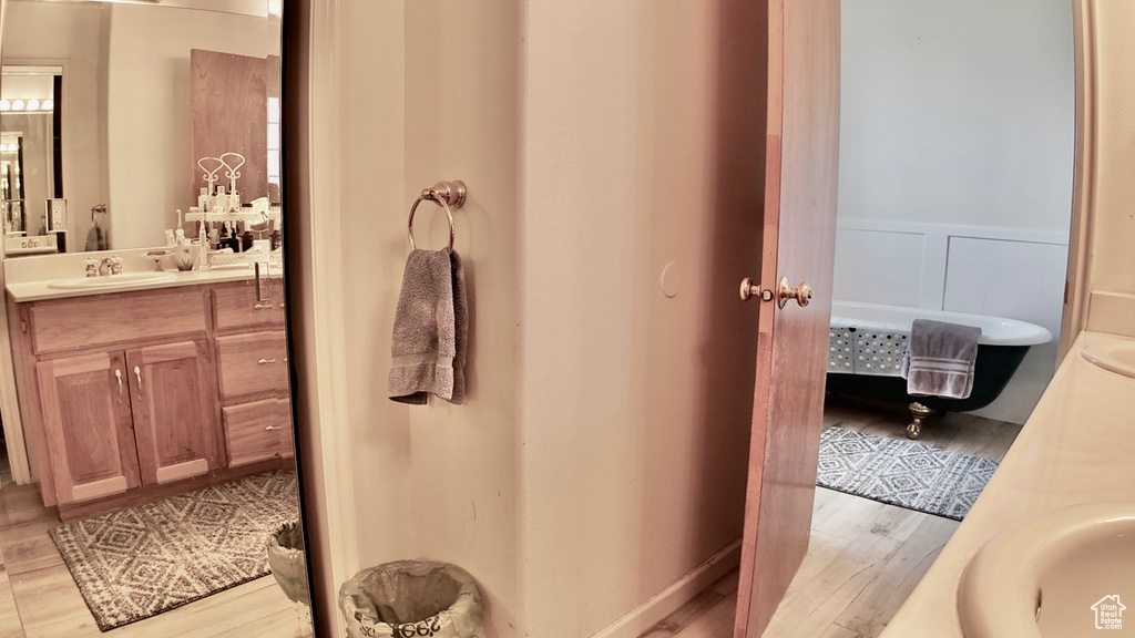 Bathroom with a wainscoted wall, vanity, and wood finished floors