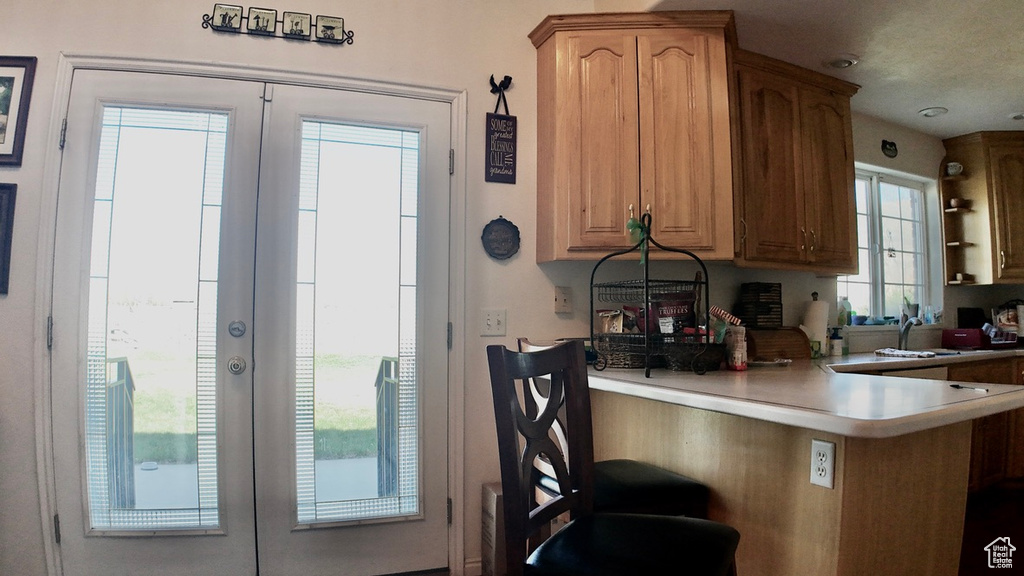 Kitchen featuring a kitchen bar, a peninsula, french doors, and light countertops