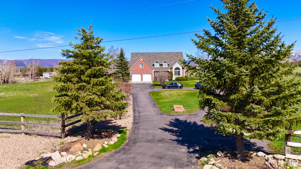 Cape cod house with a mountain view, driveway, a front lawn, a garage, and fence
