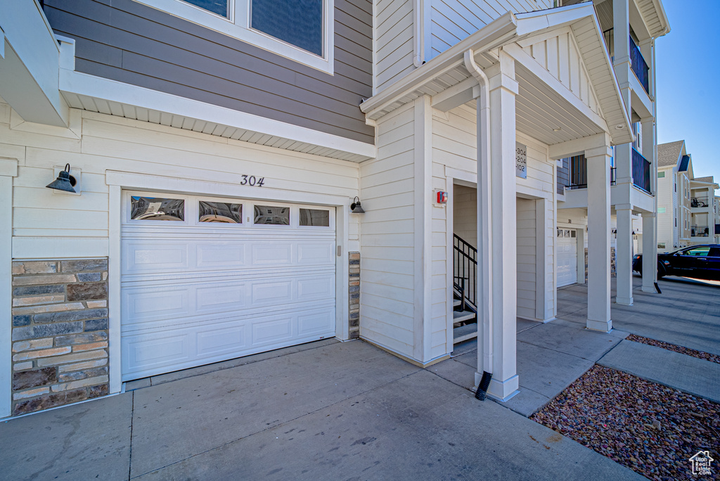View of side of home with an attached garage, stone siding, and concrete driveway