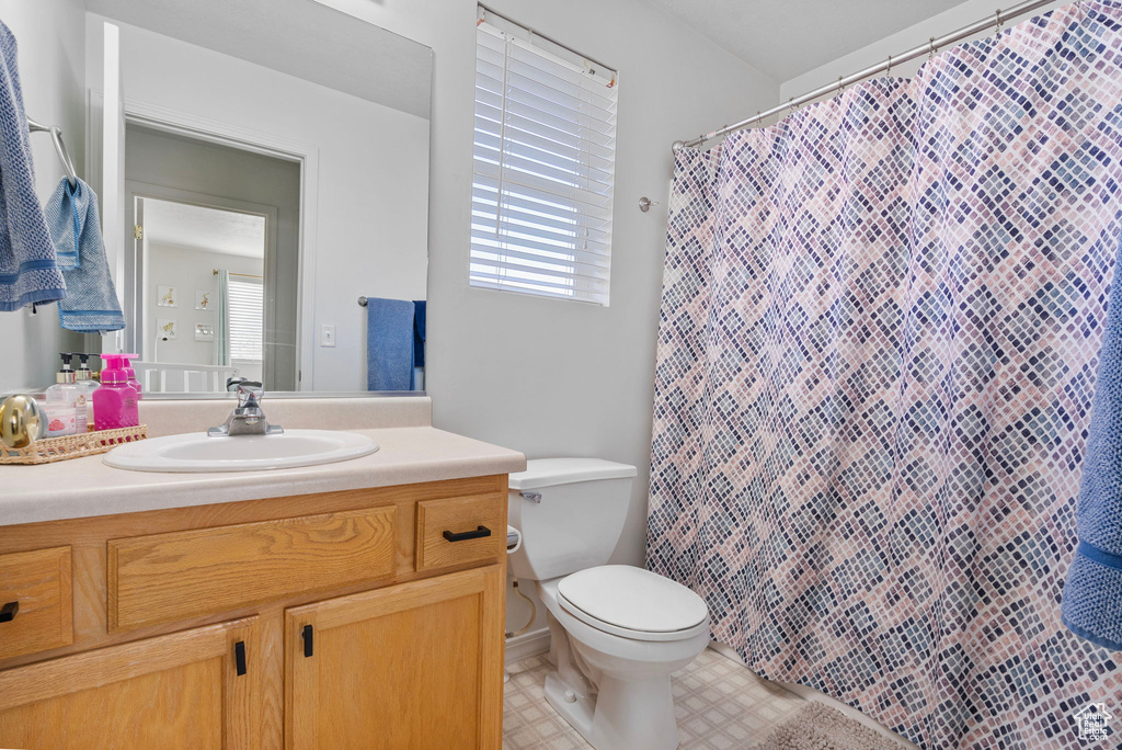 Bathroom featuring toilet, vanity, and a shower with curtain