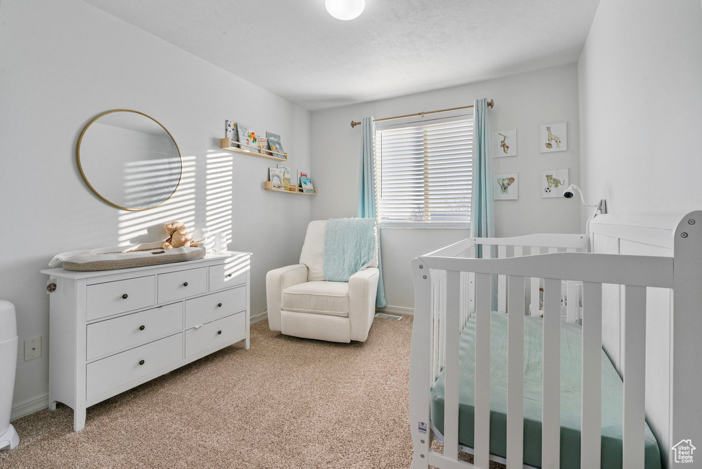 Bedroom featuring light colored carpet and a crib