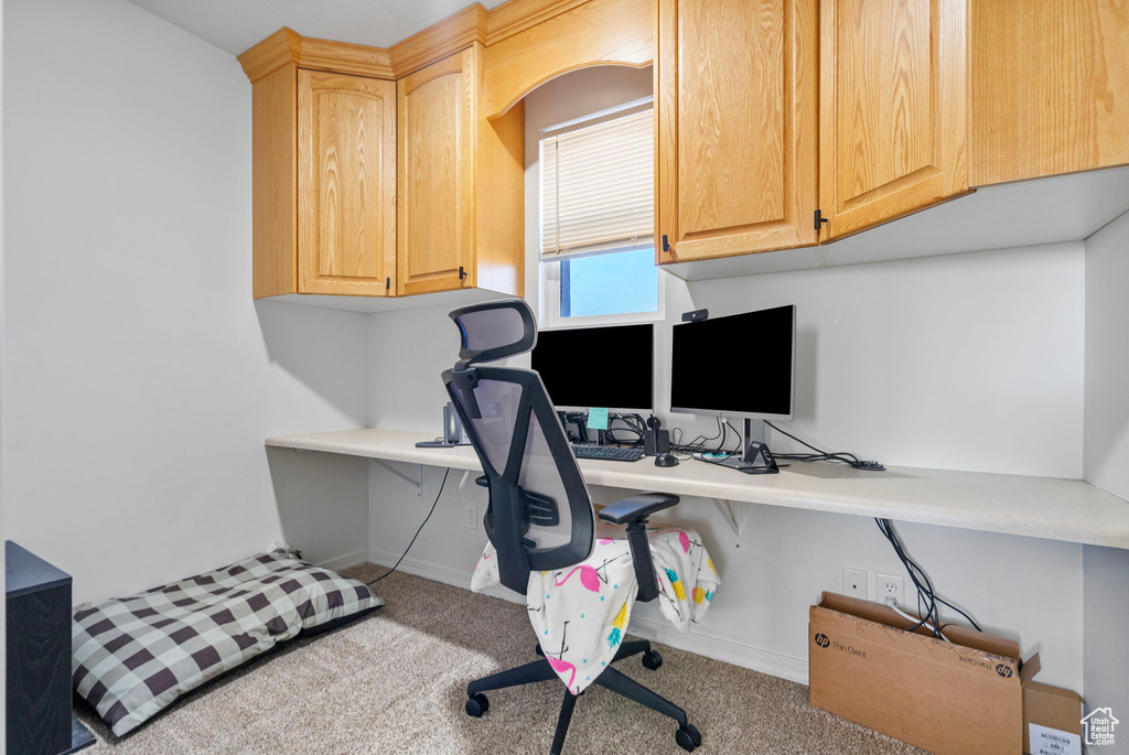 Office area featuring built in desk, baseboards, and carpet floors