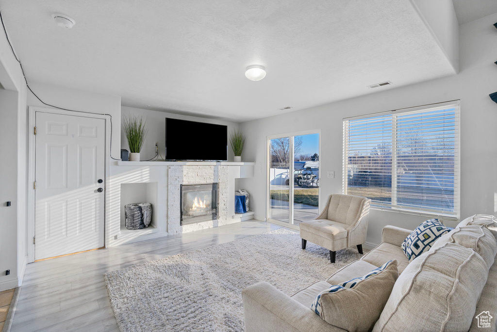 Living room with a fireplace, visible vents, baseboards, and wood finished floors