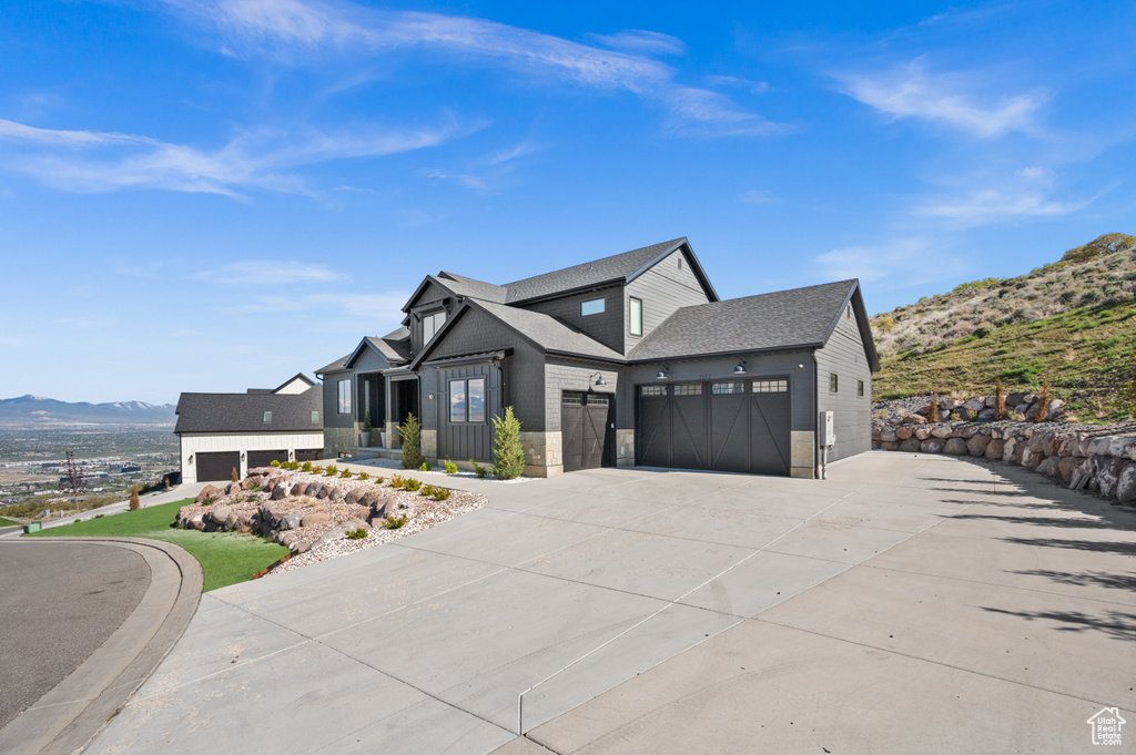 Modern inspired farmhouse with a garage, a mountain view, concrete driveway, and roof with shingles