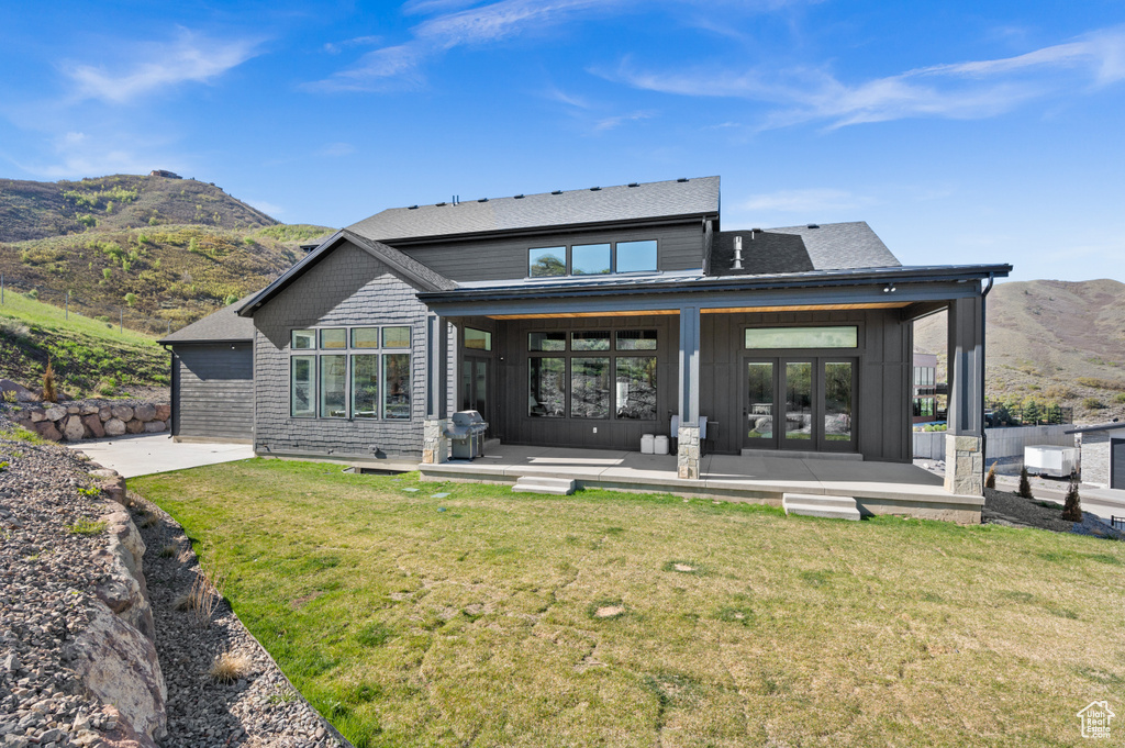 Back of property featuring a yard, a patio, a mountain view, and roof with shingles