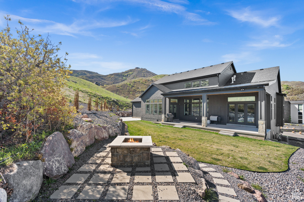 Back of property with a yard, a patio, a mountain view, and an outdoor fire pit