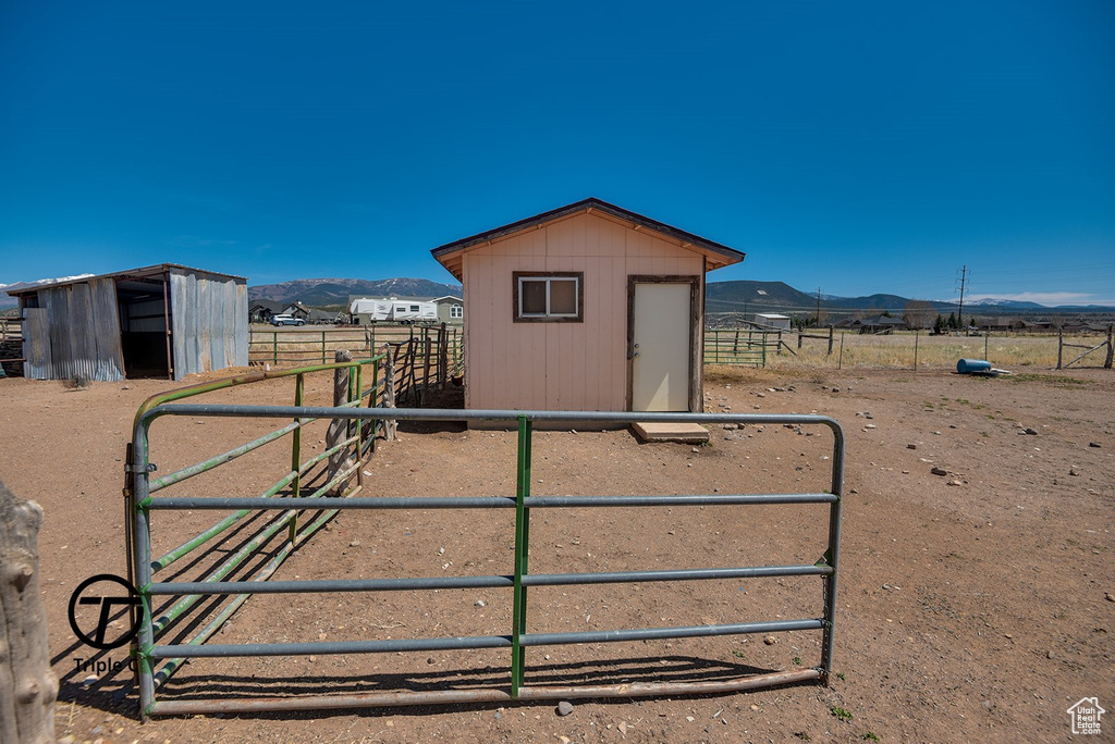 View of outdoor structure featuring a rural view, a mountain view, and an outbuilding