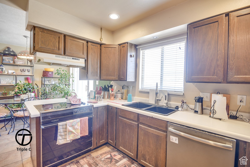 Kitchen with dishwasher, a sink, light countertops, under cabinet range hood, and stove