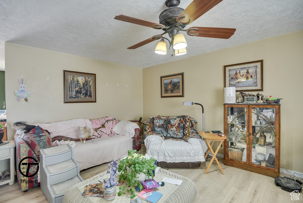 Living area featuring ceiling fan, wood finished floors, and a textured ceiling