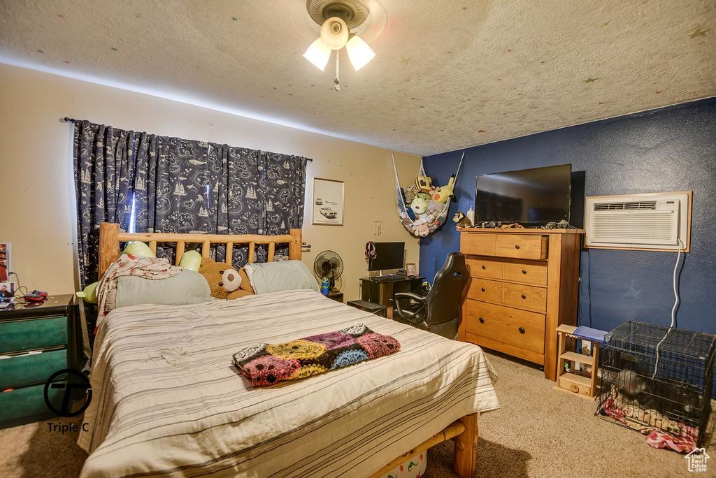 Bedroom featuring an AC wall unit, carpet flooring, and a textured ceiling