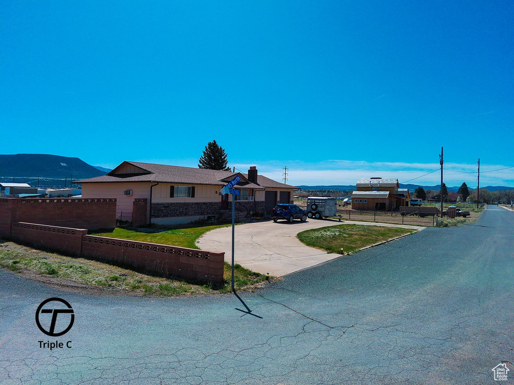 View of front facade with a front yard, driveway, and fence