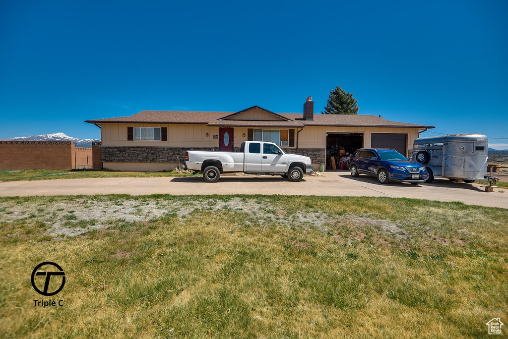 Single story home with driveway, stone siding, a garage, and a chimney