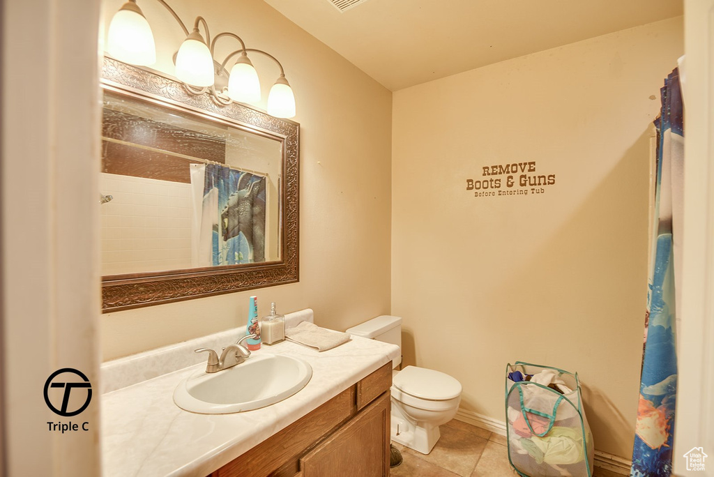 Bathroom with tile patterned floors, curtained shower, vanity, and toilet