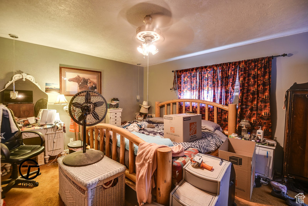 Carpeted bedroom featuring ceiling fan and a textured ceiling