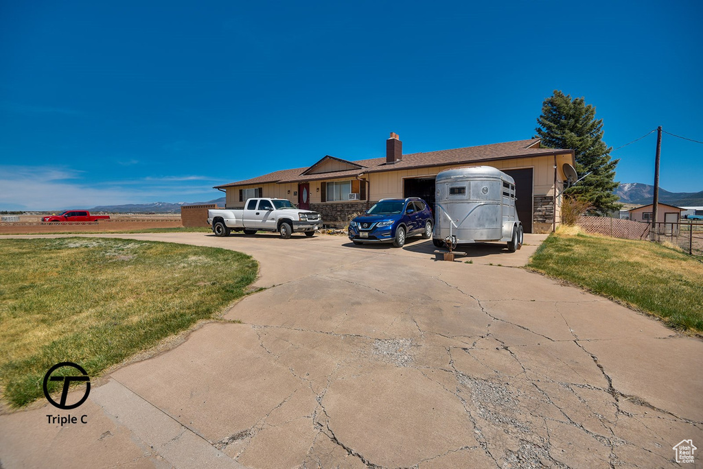 Ranch-style home with concrete driveway, a front yard, a chimney, and an attached garage