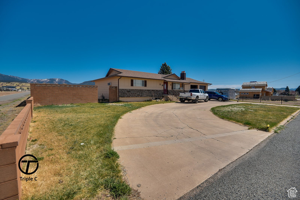 View of front facade featuring a front yard, fence, and driveway