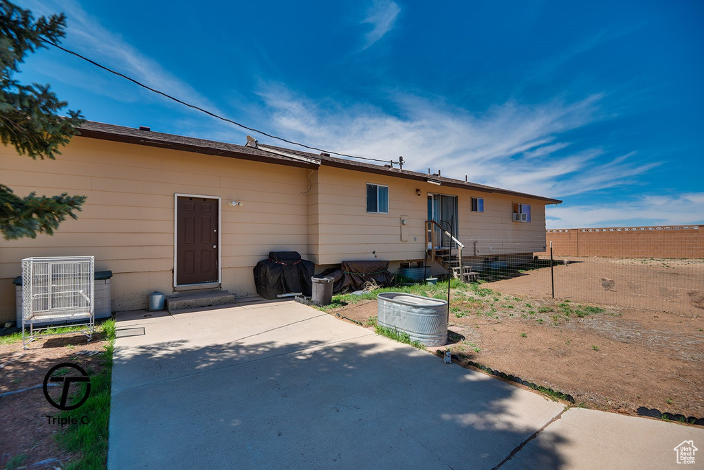 Back of property featuring entry steps, fence, central AC unit, and a patio