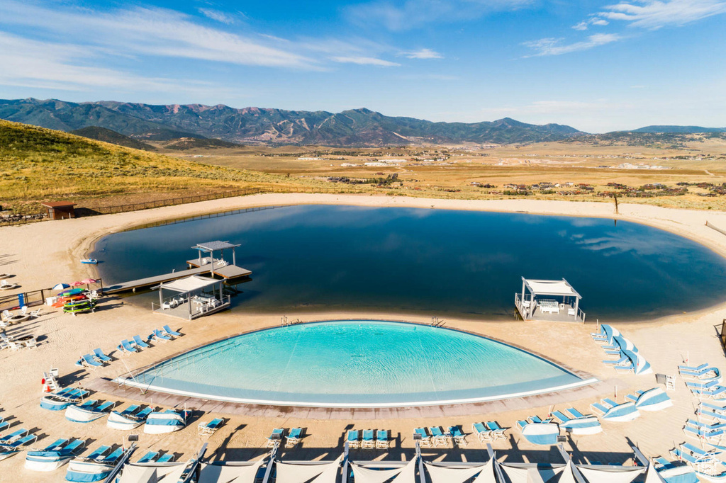 View of pool featuring a dock and a water and mountain view