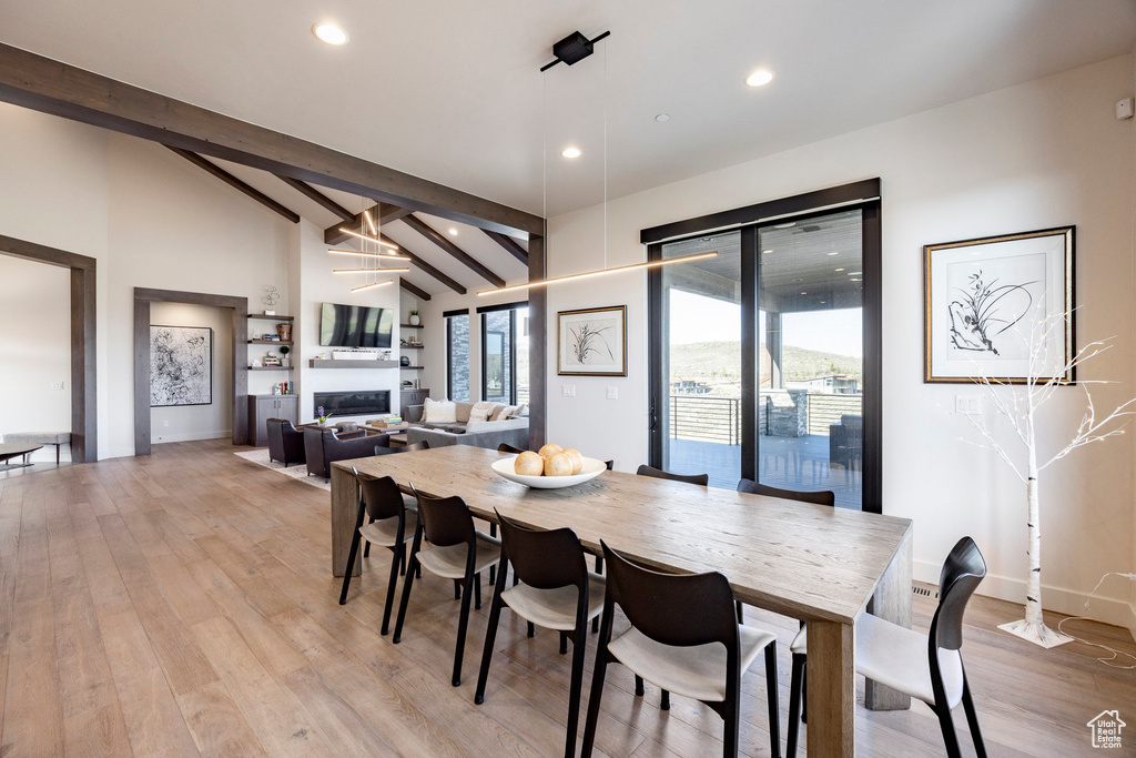 Dining area featuring recessed lighting, light wood finished floors, lofted ceiling with beams, and a fireplace