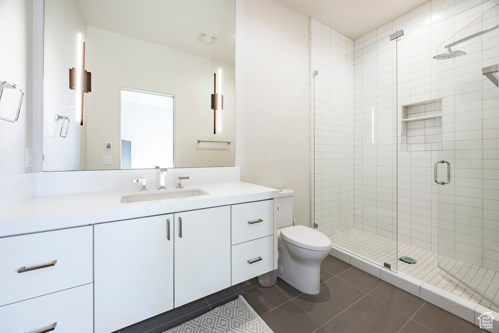 Full bath featuring tile patterned floors, toilet, a stall shower, and vanity