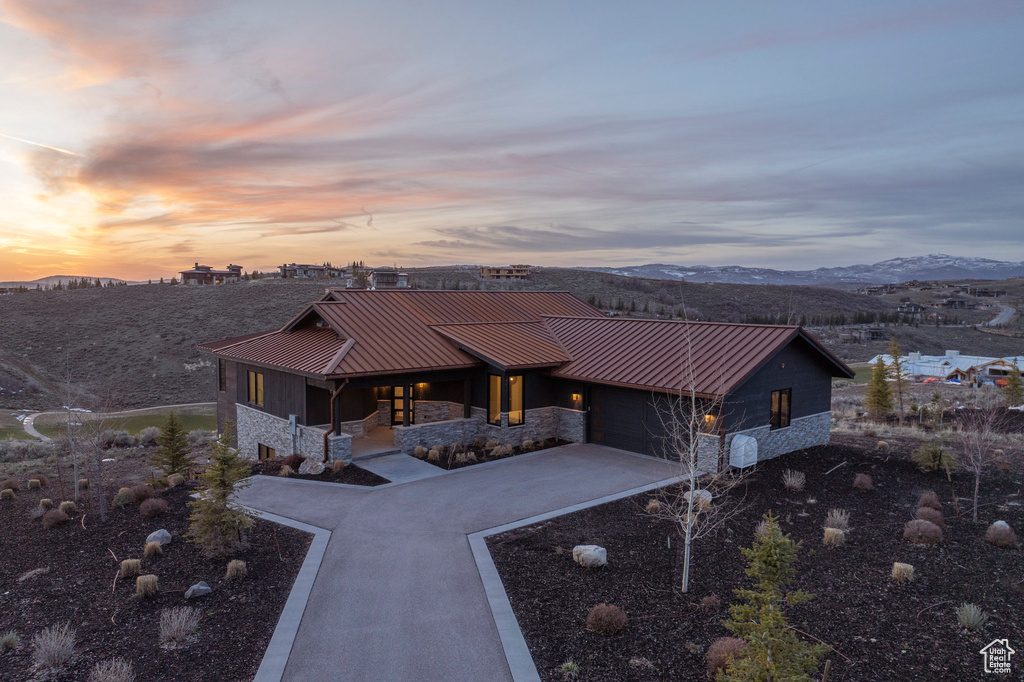 View of front of house with a standing seam roof, metal roof, stone siding, a mountain view, and concrete driveway