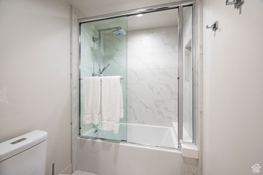 Bathroom with bath / shower combo with glass door and toilet