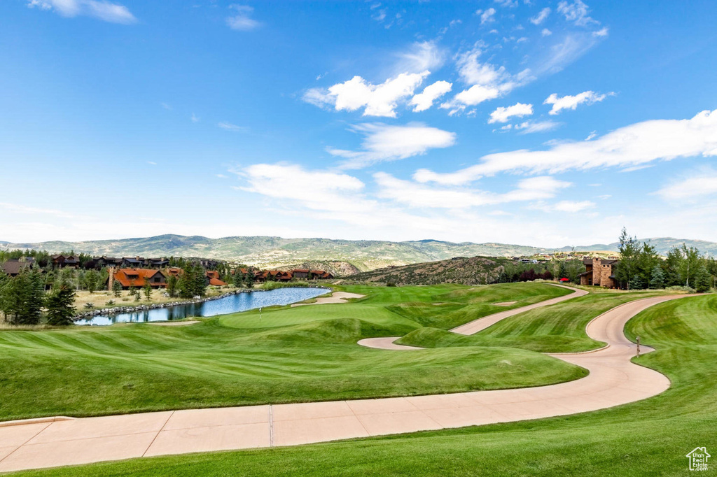 View of property's community with view of golf course, a yard, and a water and mountain view