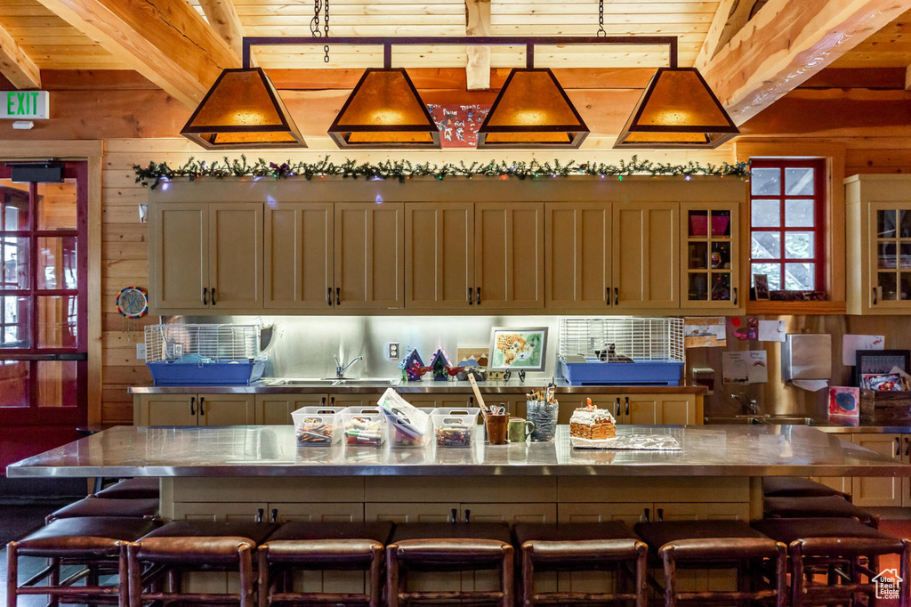 Kitchen featuring beamed ceiling, wooden ceiling, a kitchen breakfast bar, and wood walls