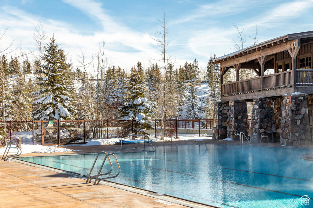 Snow covered pool featuring a patio, a community pool, and fence