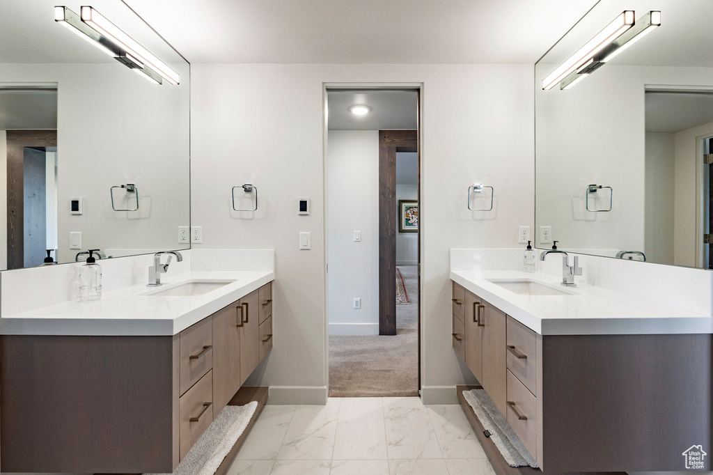 Bathroom with two vanities, marble finish floor, a sink, and baseboards