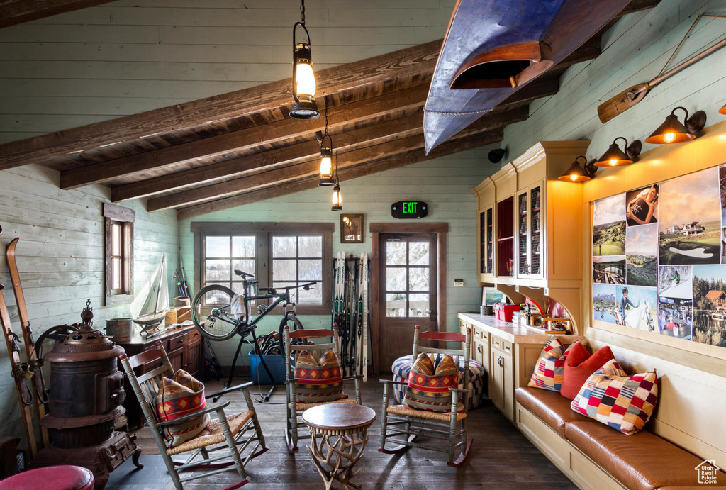 Living area featuring dark wood-type flooring, wood ceiling, wooden walls, and vaulted ceiling with beams