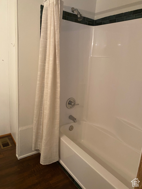 Bathroom with shower / bathtub combination with curtain and wood finished floors
