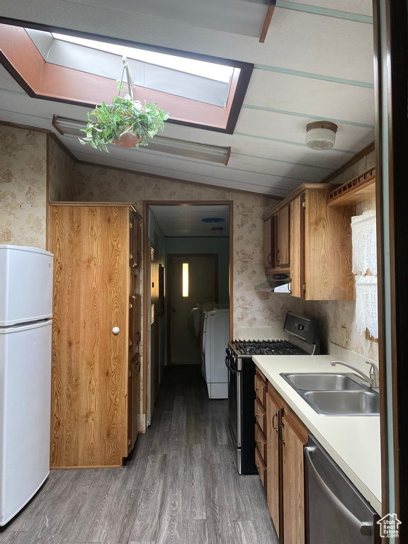 Kitchen with stainless steel appliances, wallpapered walls, washing machine and clothes dryer, light countertops, and brown cabinetry