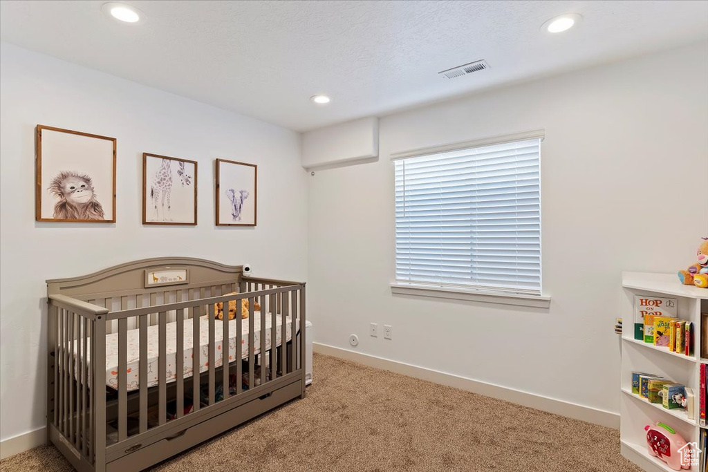 Bedroom featuring baseboards, recessed lighting, visible vents, a nursery area, and carpet