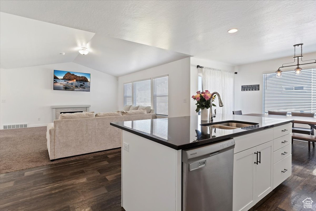 Kitchen featuring dark countertops, dark wood-type flooring, visible vents, dishwasher, and a sink