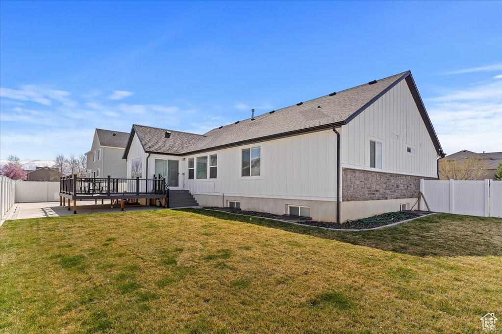 Back of house with a yard, a fenced backyard, a wooden deck, and a patio area