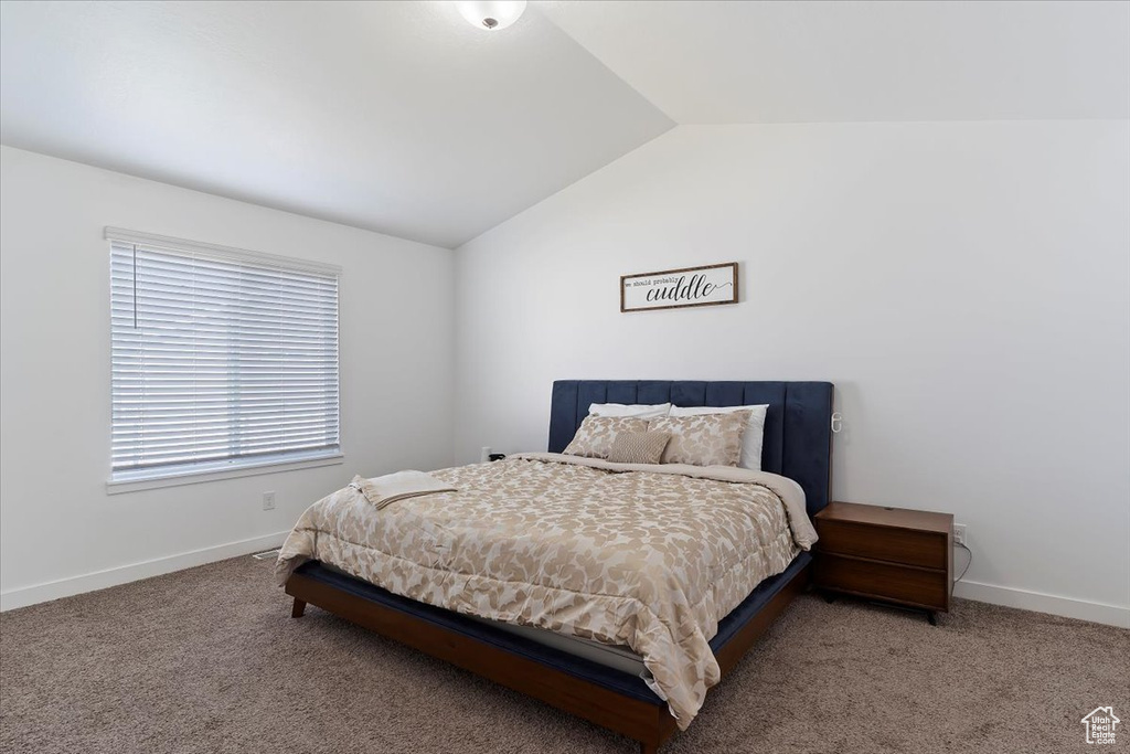 Carpeted bedroom with baseboards and vaulted ceiling