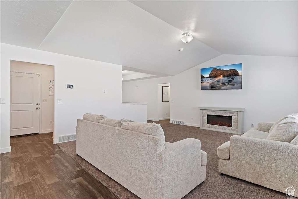 Living area with visible vents, baseboards, dark wood-style floors, and vaulted ceiling