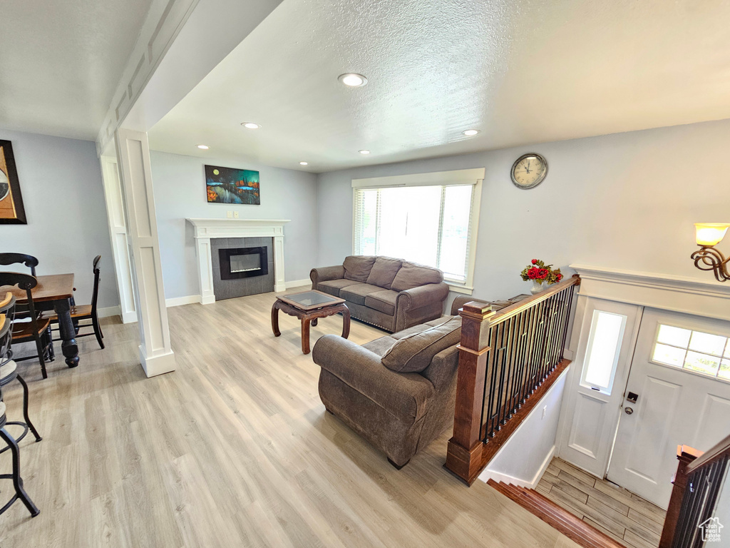 Living room featuring light wood-type flooring, recessed lighting, baseboards, healthy amount of natural light, and a tiled fireplace