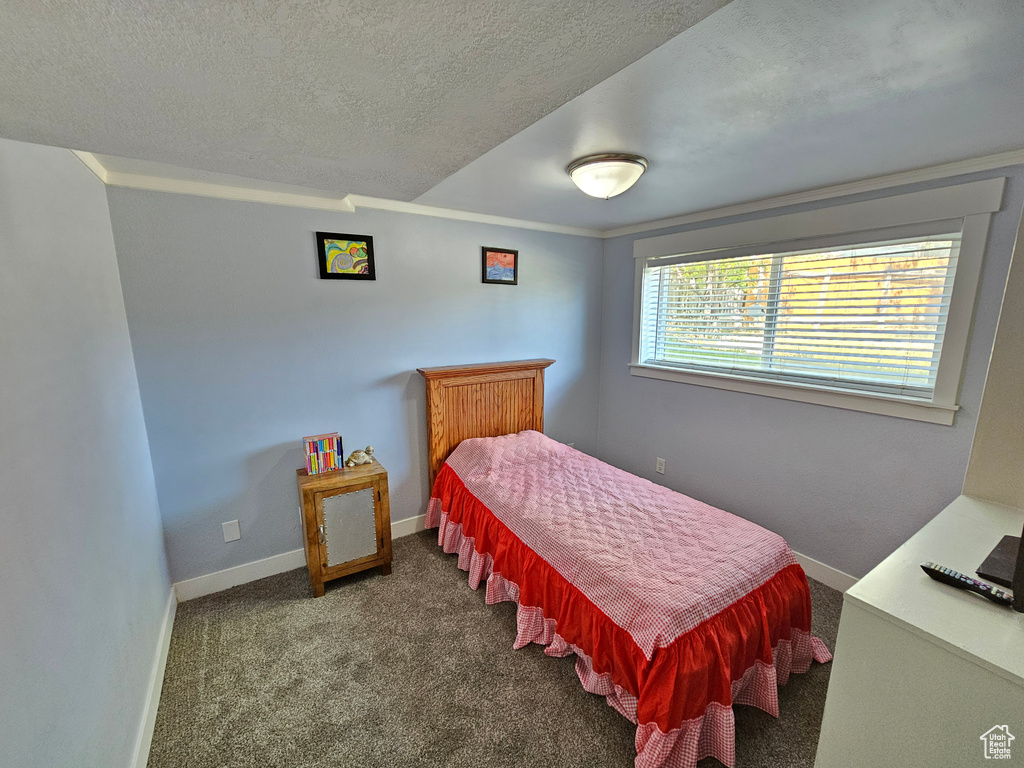 Carpeted bedroom featuring a textured ceiling, baseboards, and ornamental molding