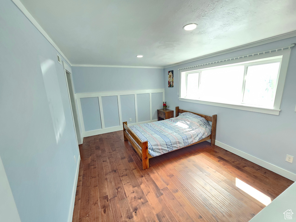 Bedroom with wood finished floors, ornamental molding, a closet, baseboards, and recessed lighting