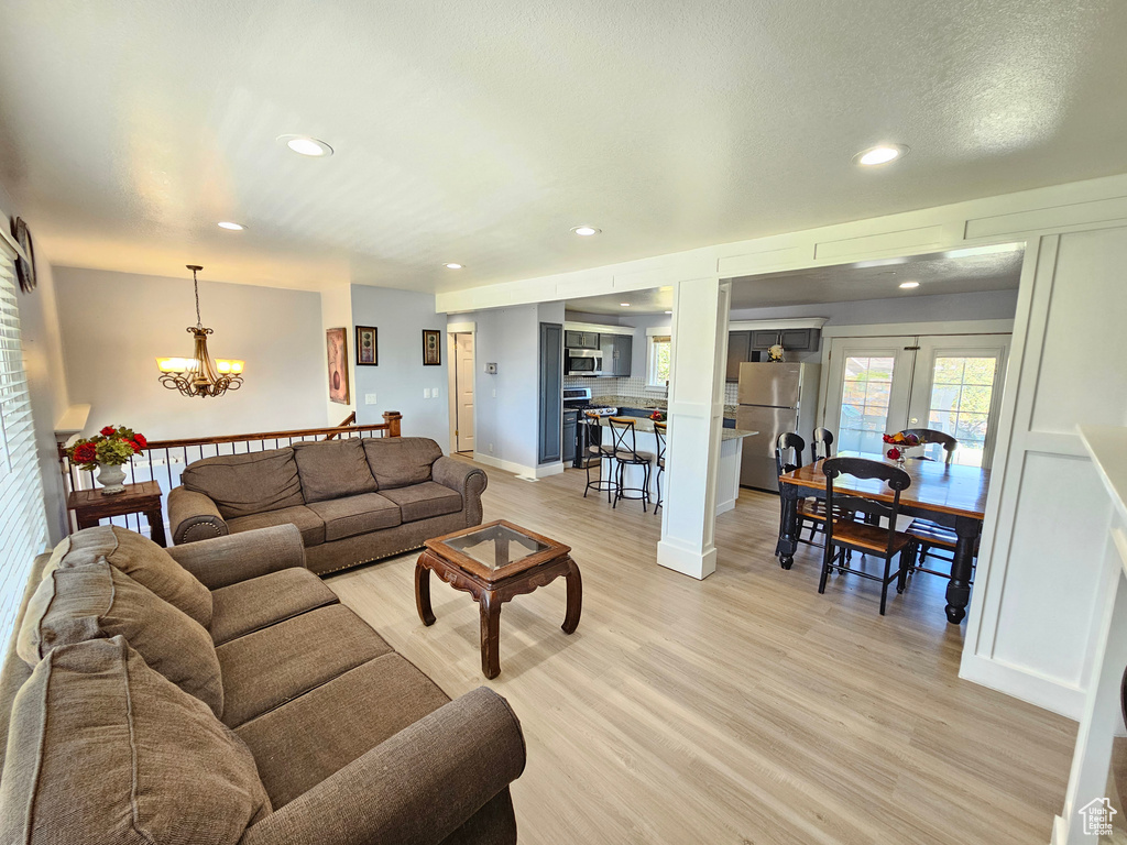 Living area with a chandelier, light wood-style flooring, and recessed lighting