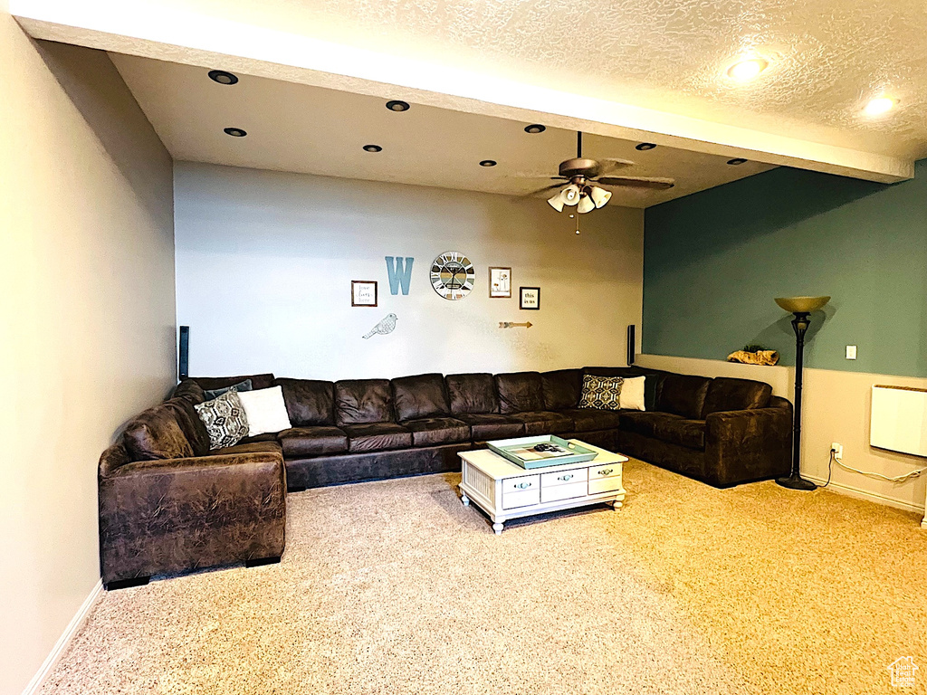 Carpeted living area featuring ceiling fan, baseboards, radiator, and recessed lighting