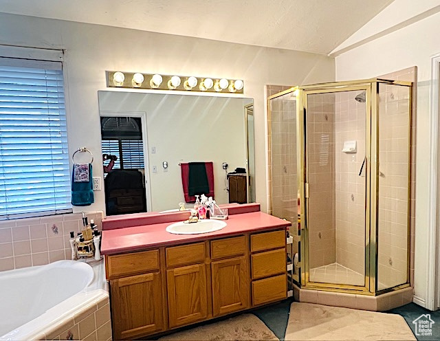 Bathroom featuring a garden tub, vanity, a shower stall, and vaulted ceiling