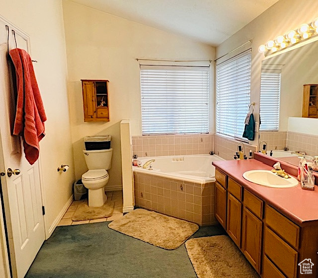Bathroom featuring a bath, lofted ceiling, toilet, and vanity