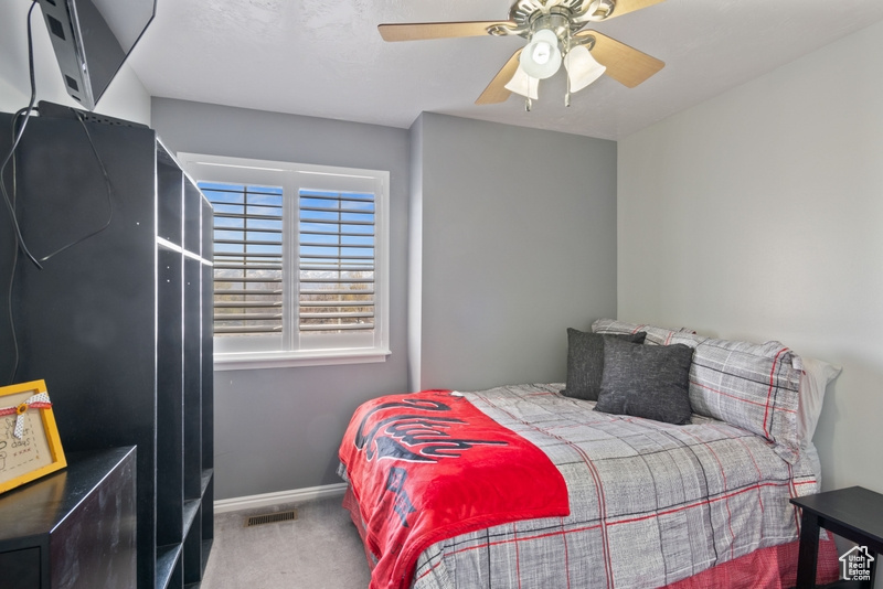 Carpeted bedroom with visible vents, baseboards, and ceiling fan
